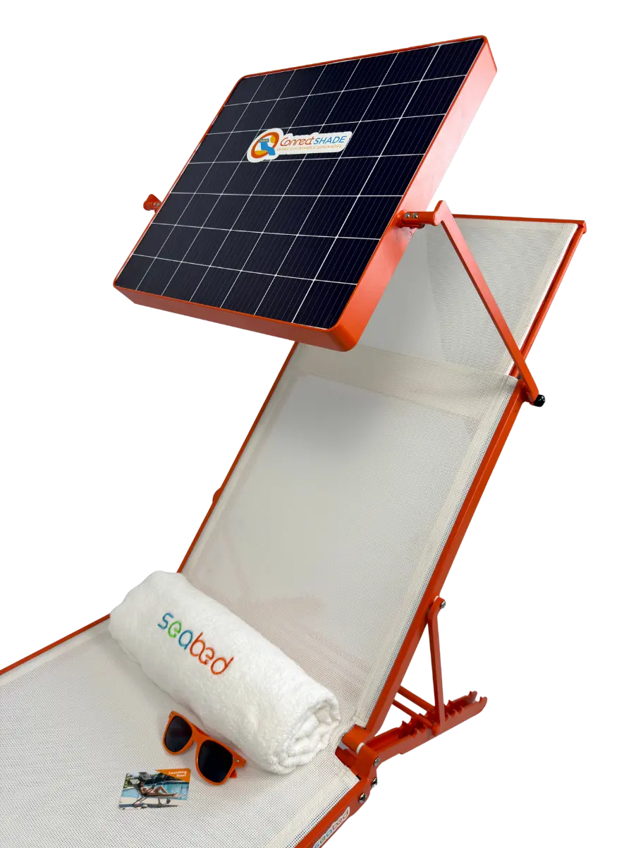 An orange solar-powered outdoor lounge chair with a built-in solar panel on a white background. The chair is shown with a white rolled towel, sunglasses, and a small accessory on the seat.